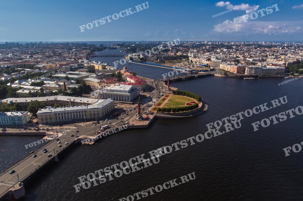 Фотография с высоты птичьего полета демонстрирует великолепный вид на Стрелку Васильевского острова, одну из самых знаковых достопримечательностей Санкт-Петербурга. Здание Биржи и Ростральные колонны являются центральными элементами этой фотографии, идеально подходящей для использования в туристических брошюрах, исторических изданиях и рекламных материалах, связанных с культурным наследием города.